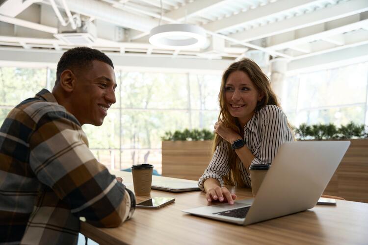 Two co-workers using laptop while working together