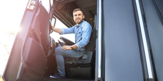 A driver sitting in the front seat of a large truck.