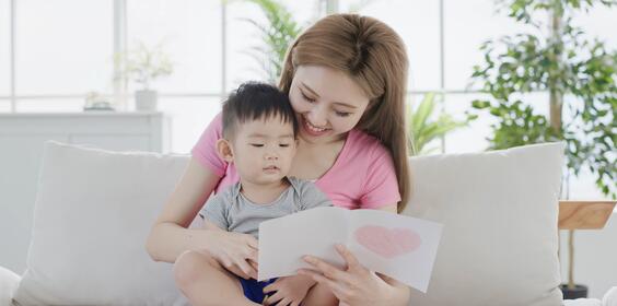 A woman reading a card with her little boy.