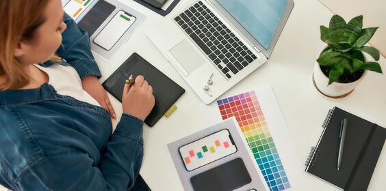 A graphic designer working on her ipad at her desk.