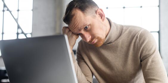 A man looking confused staring at his laptop screen.